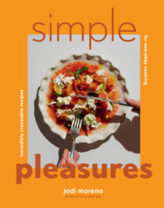 Simple Pleasures cookbook cover by Jodi Moreno shows a cheesy tomato pasta dish served in a scallop-edged pan