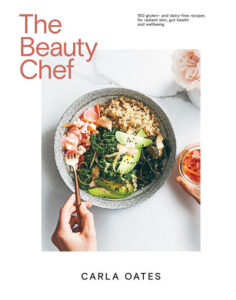 The Beauty Chef cookbook cover by Carla Oates shows a bowl of greens and grains held by two hands over a white tablecloth